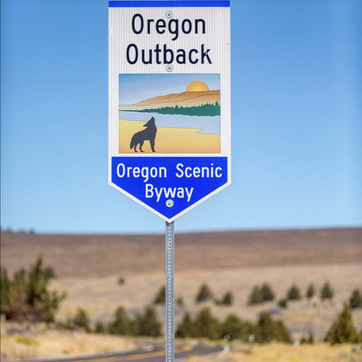 Oregon Outback Scenic Byway road sign with coyote silhouette against the high desert landscape
